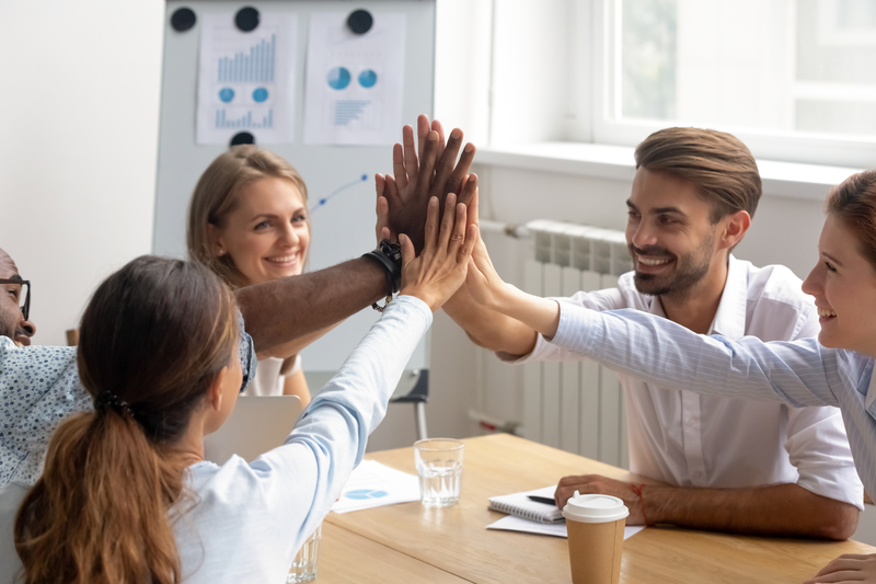 Happy motivated smiling diverse members of business team join hands palms together. Excited employees giving high five congratulate each other with successful teamwork, common goal achievement